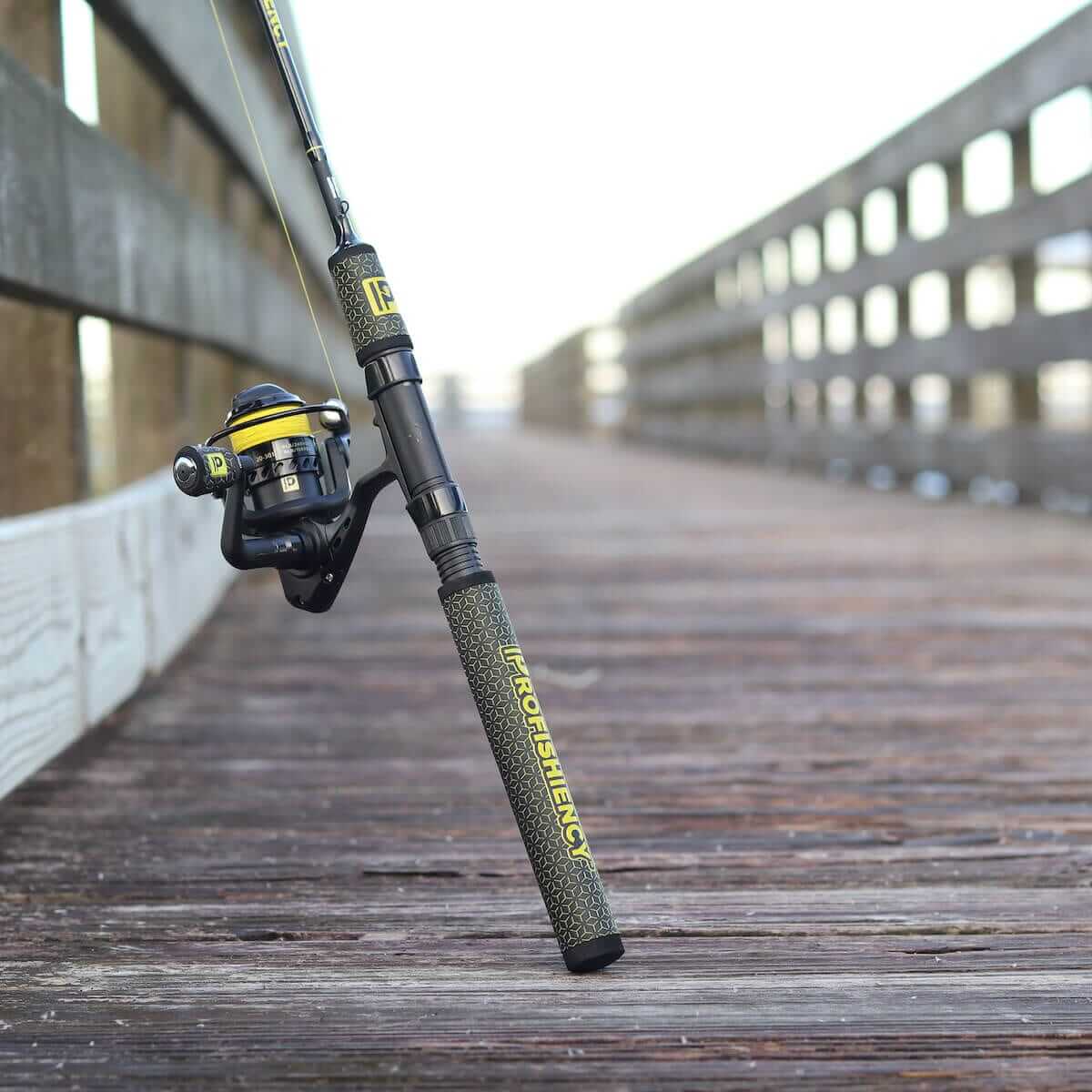 Spinning rod and yellow-accent reel leaning on wooden pier; brand text PROFISHIENCY and logo P visible
