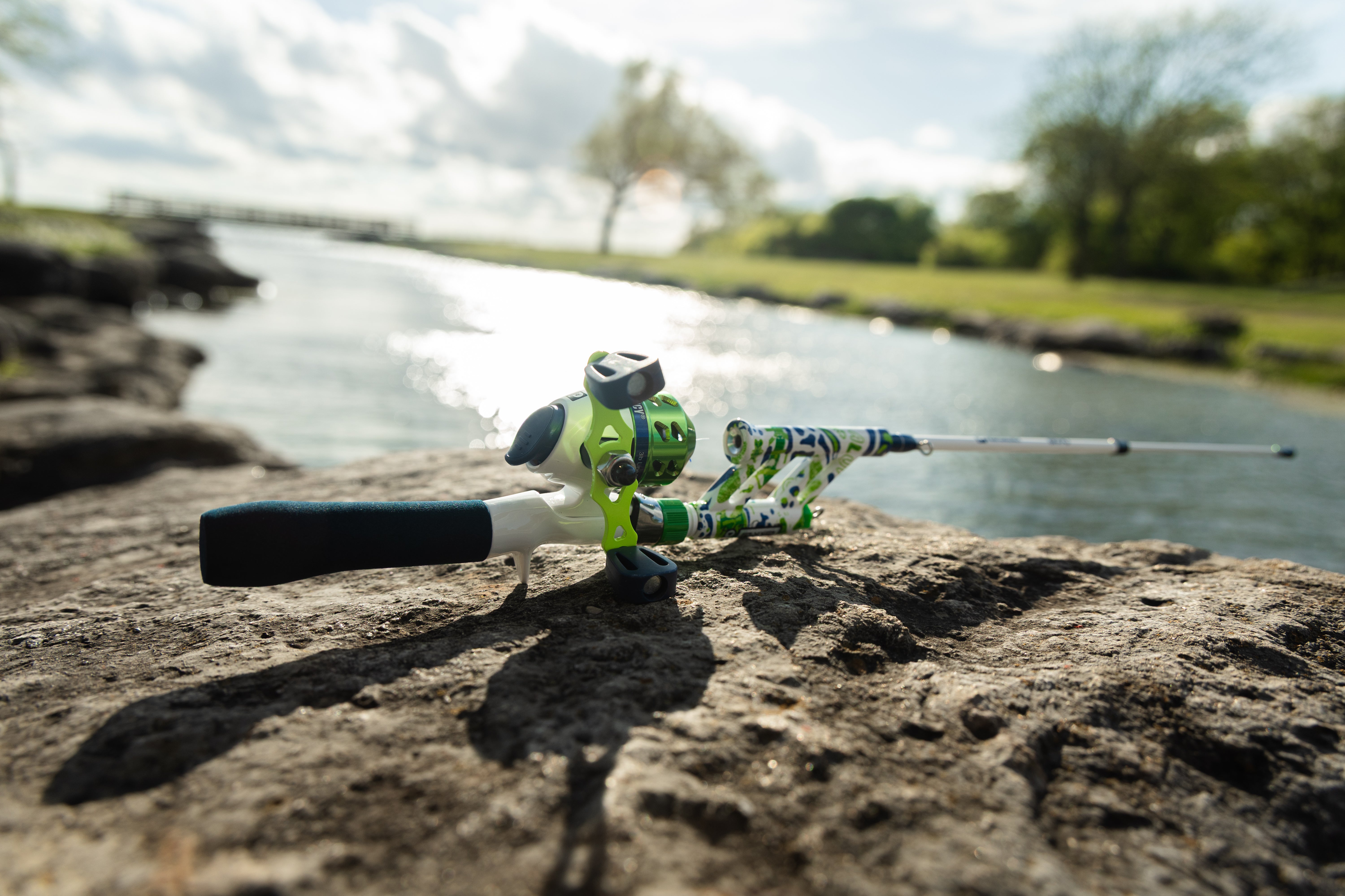 Close-up view of Green Briyo Tiny Pocket Combo showcasing its bright green spincast reel and compact rod against a rocky outdoor background