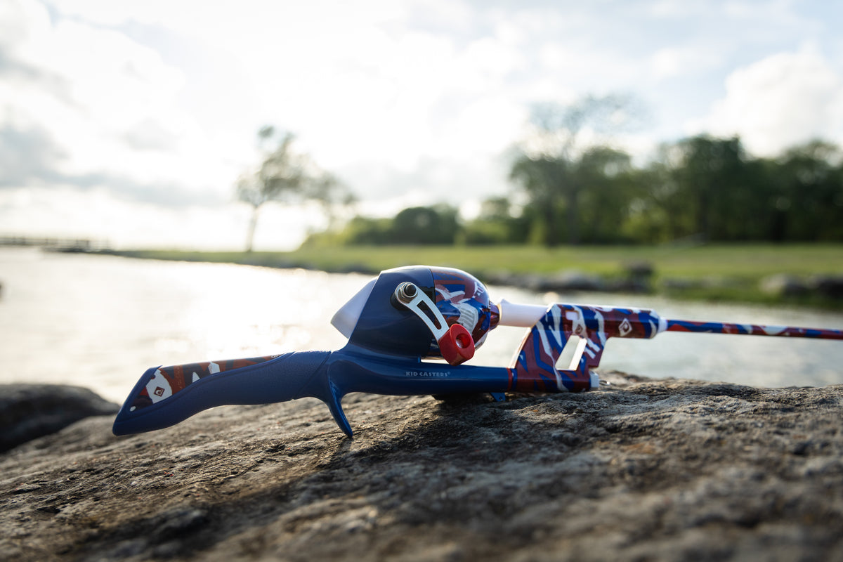 Side view of Americana Tangle-FREE Combo showcasing its blue, red, and white design on a lakeside rock