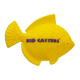 Top-down view of yellow fish-shaped practice casting plug showing molded scales and purple 'KID CASTERS' text on black background