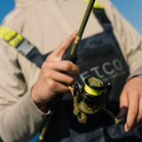 Close-up of Profishiency Retro Spinning Reels - Clam Pack showcasing classic-camo design in an angler’s hands