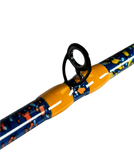 Close-up of baitcasting rod guide with yellow thread wraps on a blue rod blank with orange and yellow splatter finish