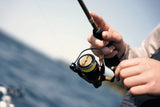 Angler reeling a black and gold spinning rod over the water