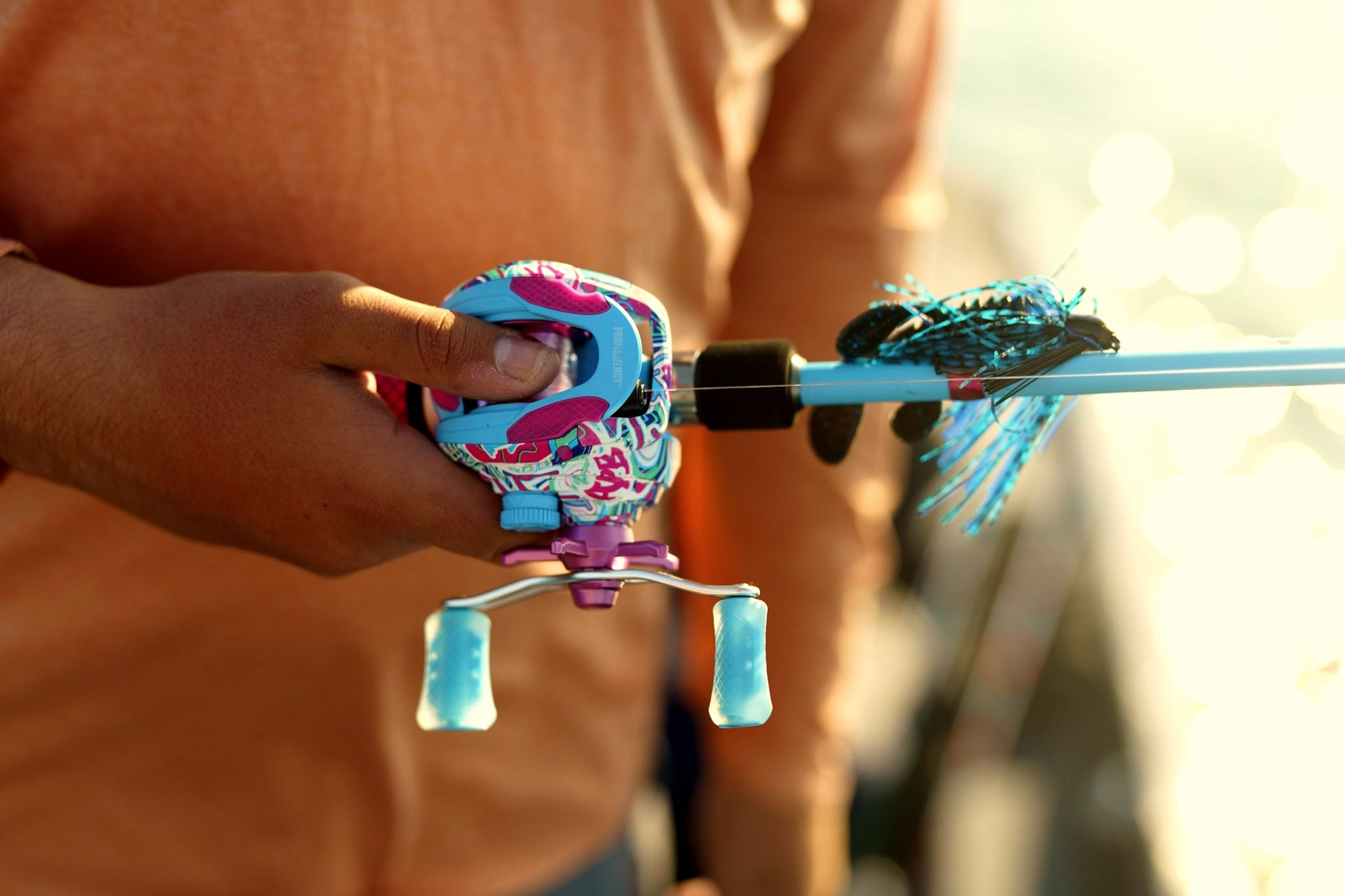 Close-up view of Wild Child Baitcast Combo showcasing its colorful reel and blue rod with a hand holding it