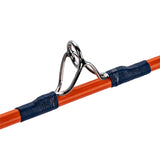 Close-up of a chrome fishing rod guide secured with dark blue thread wraps on an orange rod blank.
